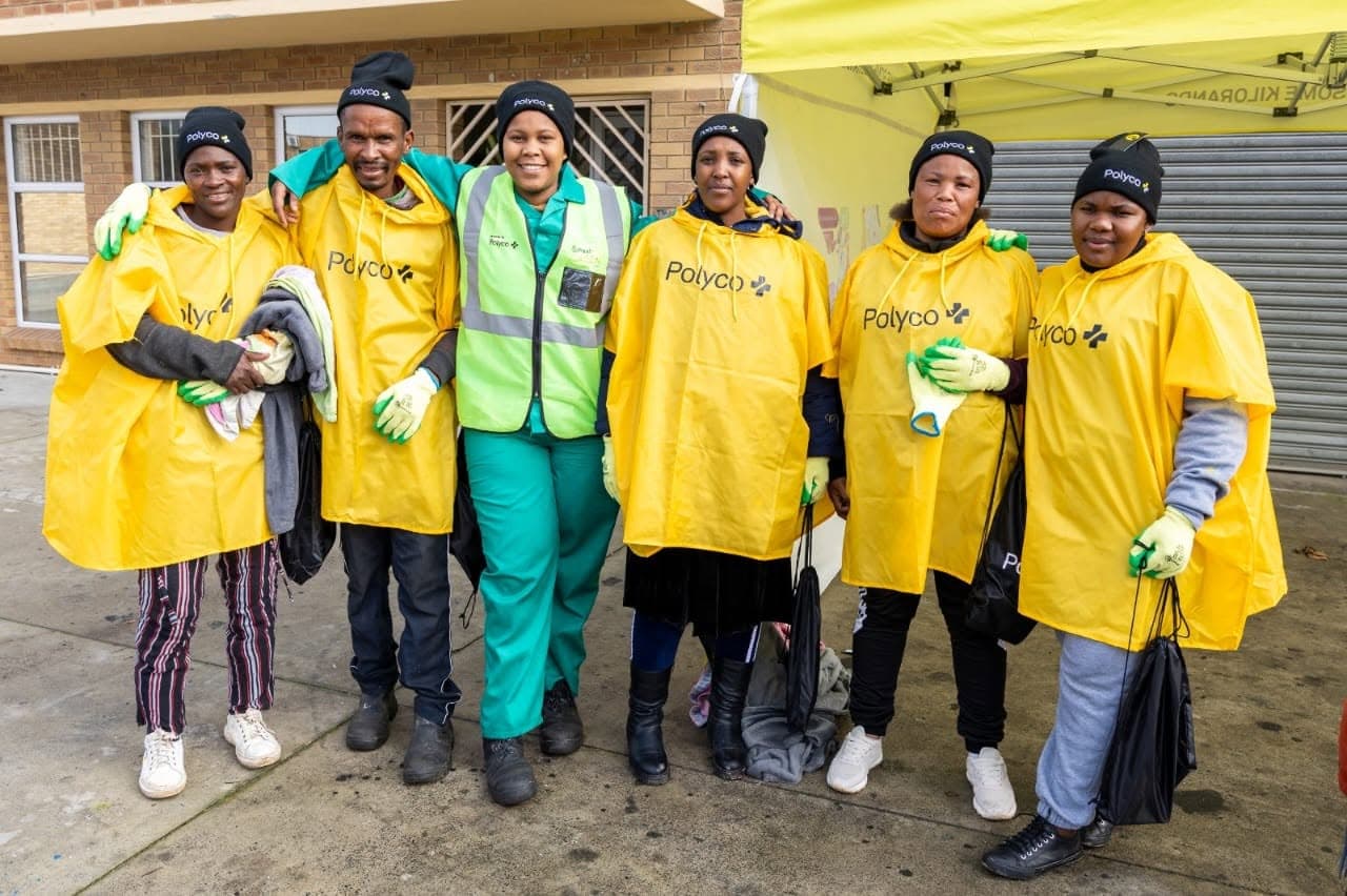 A group of community collectors in Polyco ponchos with a WasteGo Green staff member in a green hi-vis vest