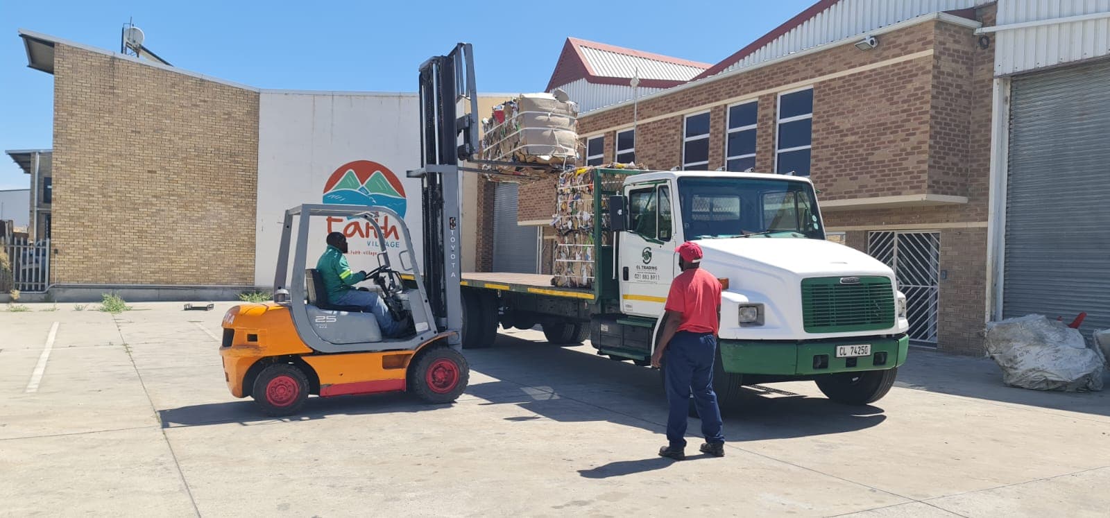 A forklift loading a pallet of baled paper and cardboard onto a flatbed truck at the WasteGo Green depot