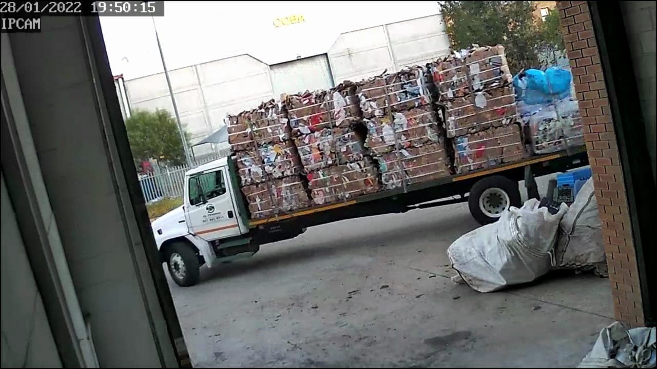 A flatbed truck fully loaded with baled recyclables leaving the WasteGo Green depot