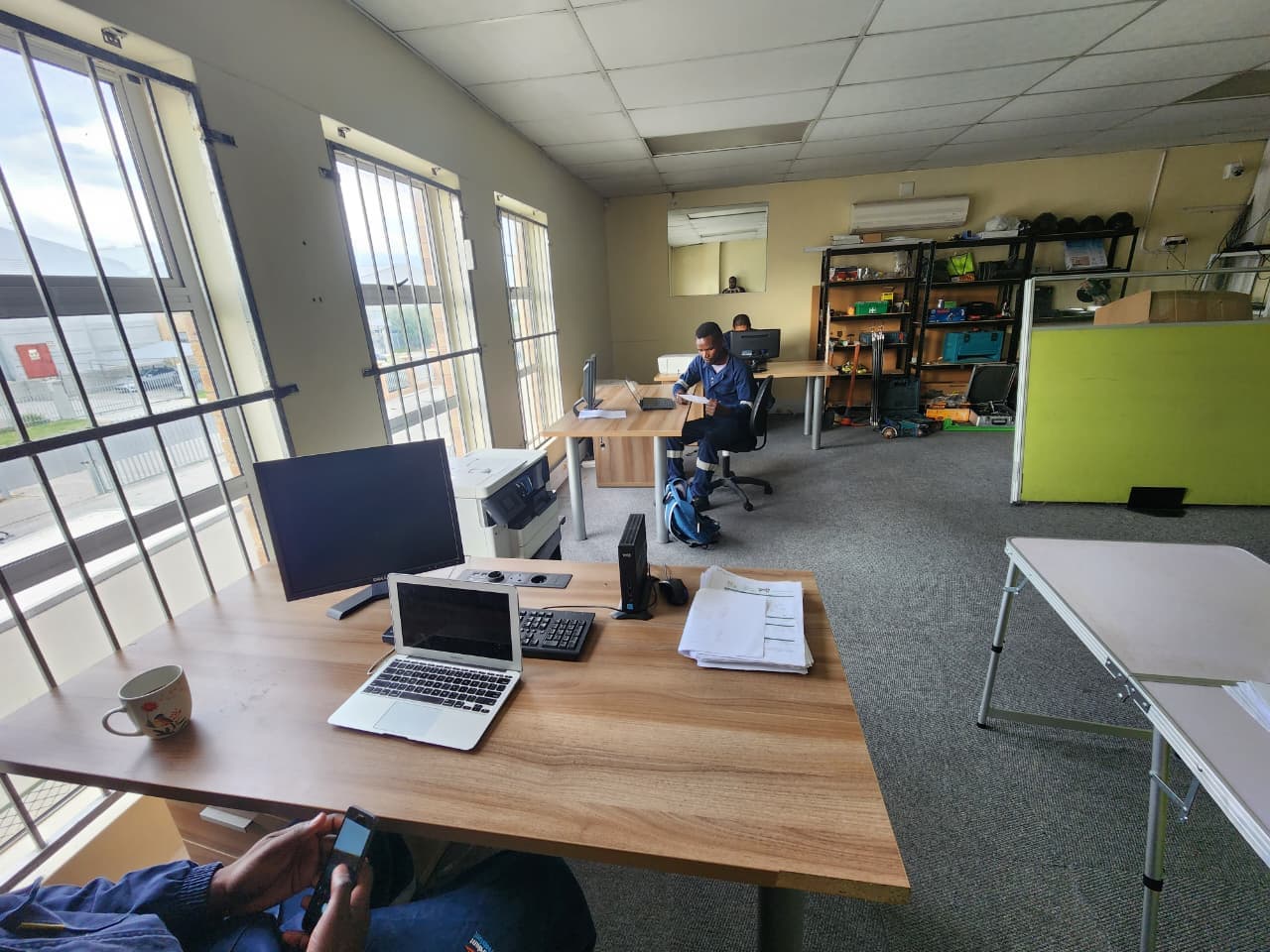 WasteGo Green staff working at desks with laptops and a tools shelf in the operations office