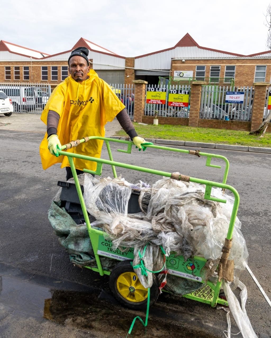 A collector pushing the green recycling trolley loaded with clear plastic film through a Montague Gardens street