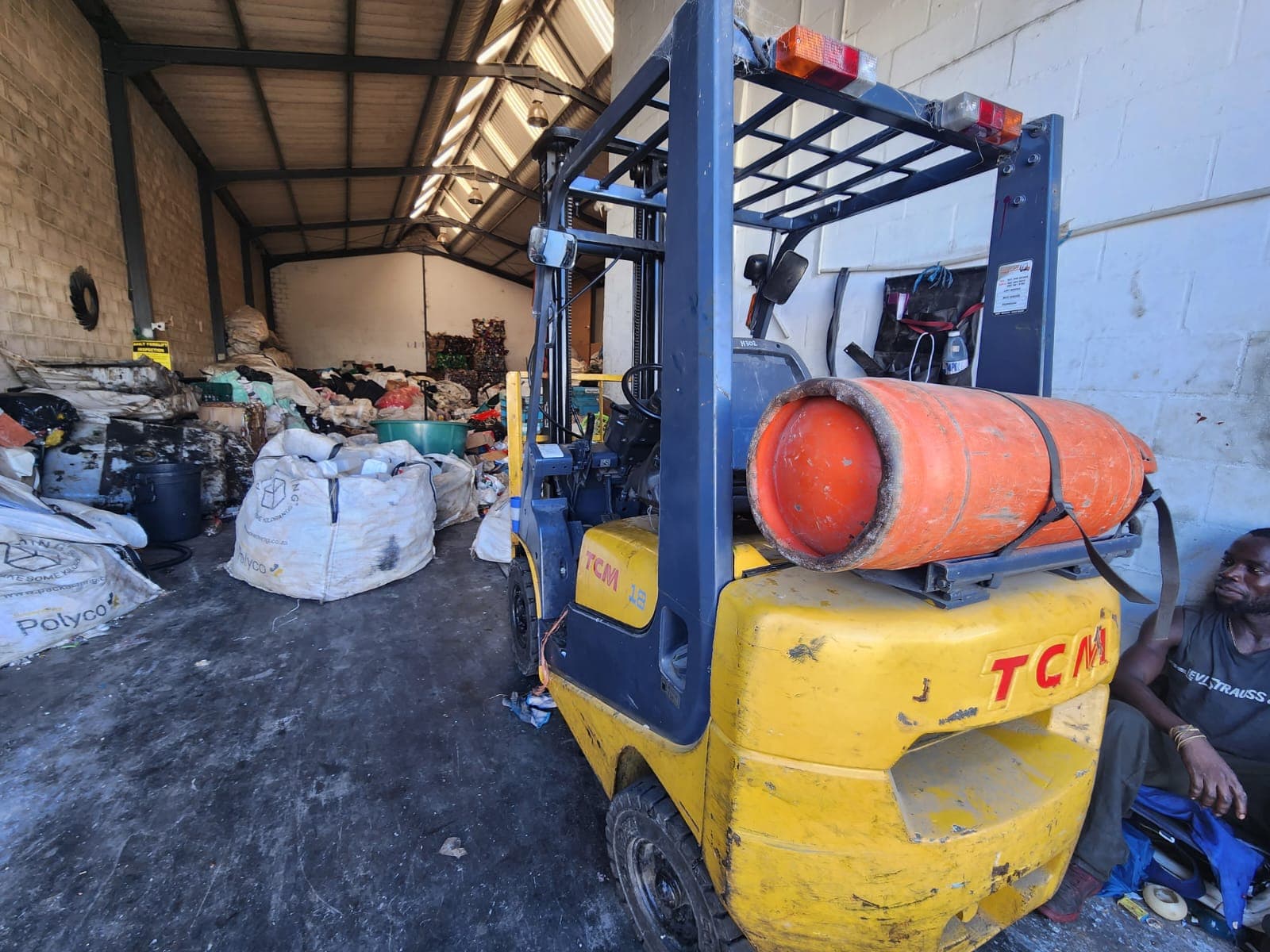 A TCM forklift inside the warehouse beside Polyco bulk bags of recyclables